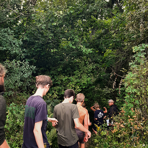 Eine Gruppe Jugendlicher geht gemeinsam in den Wald.